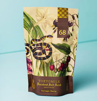 Bag of TokyoMilk Decadent Salt Soak in Savage Belle scent features metallic gold foil lettering and accents and an illustration of a striped snake among lush florals