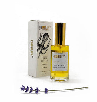 Glass bottle of Formulary 55 Sea Salt & Lavender Nourish Daily Body Oil with gold cap alongside white gift box with octopus design and a sprig of lavender in the foreground
