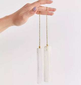 Model's hand holds the gold chains attached to two elongated pieces of selenite