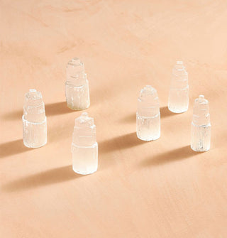Collection of whitish-clear selenite "towers" on a terracotta backdrop
