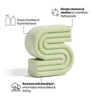 S-shaped bar of ribbed green solid shampoo is labeled with its key benefits: saves 2 bottles of liquid shampoo, deeply cleanses and clarifies, and is enriched with Dandrilys®