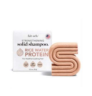 Muted orange S-shaped ribbed bar of Kitsch Rice Water Protein Strengthening Solid Shampoo next to its box packaging