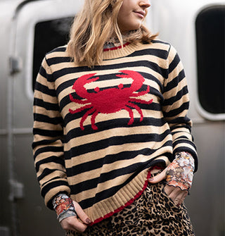 Model wears a beige and black striped sweater with red crab design on the front