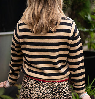 Model facing away from the camera wears a beige and black striped sweater with red trim