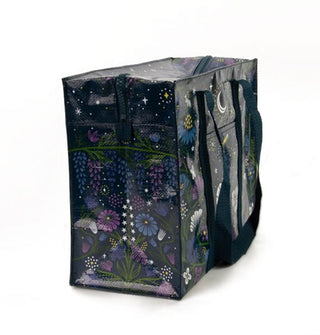 Rectangular black tote bag with dark blue woven handles features all-over floral and celestial print in blues, purples, and white with yellow accents