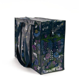 Rectangular black tote bag with dark blue woven handles features all-over floral and celestial print in blues, purples, and white with yellow accents