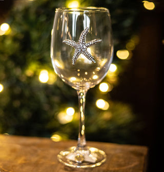 Twinkling tree lights shine through a clear wine glass with a silver rhinestone-encrusted starfish decal on its bowl
