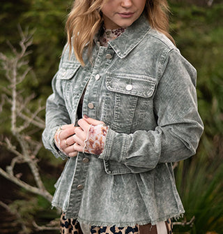 Model wears a stone wash-effect blue-gray corduroy peplum jacket against a grassy backdrop