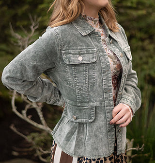 Model wears a stone wash-effect blue-gray corduroy peplum jacket against a grassy backdrop