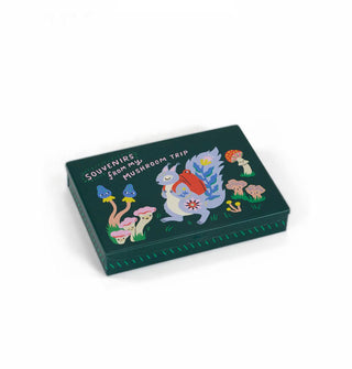 Flat dark green rectangular box featuring whimsical illustration of a squirrel wearing a red backpack among anthropomorphic mushrooms says, "Souvenirs from my mushroom trip"