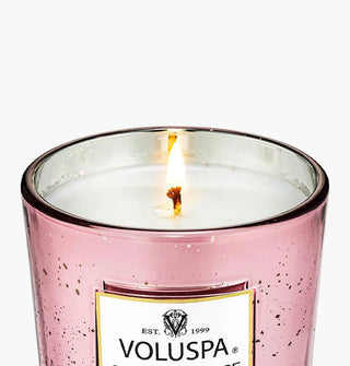 Closeup of the lit wick inside a speckled pink glass Voluspa candle jar