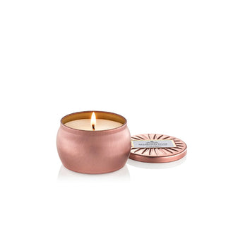 Pink candle tin with matching embossed lid removed and set to the side to reveal one lit wick