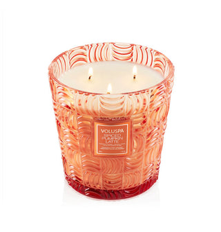 Lit three-wick Spiced Pumpkin Latte Voluspa candle in an embossed orange glass vessel