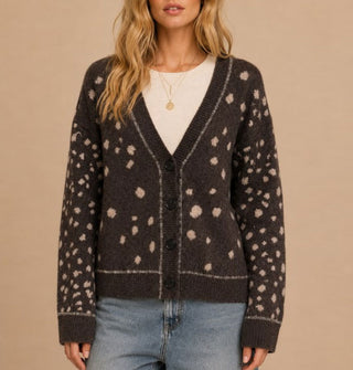 Model wears a brown V-neck cardigan with light spots all over and a thin light line along the neckline, button placket, and sleeve cuffs