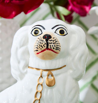 Closeup of the facial features on a white ceramic Staffordshire dog statue with gold collar and chain leash details