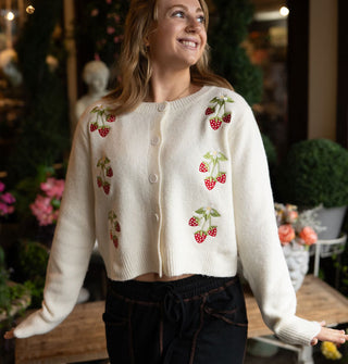 Smiling model wears a white cardigan with strawberry embroidery