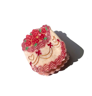 Hair clip designed to resemble a heavily decorated cake with strawberries on top