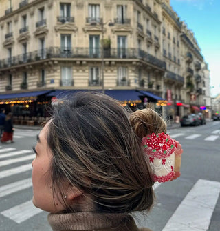 Model standing on a city square wears a strawberry cake hair clip in a twist updo