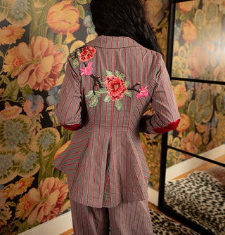 The back of a structured gray blazer with red pinstripes features colorful embroidered floral appliqués and red velvet elbow patches