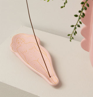 Flecked pink incense holder with gold outline illustration of a sleeping woman