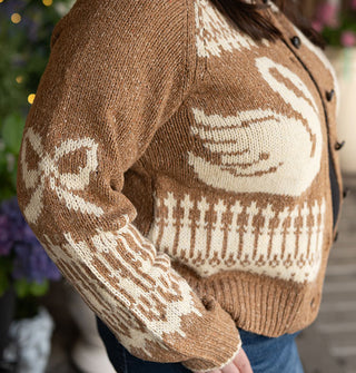SIde view of a brown button-down cardigan with white swan, bow, and other designs