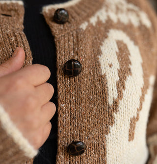 Closeup of the brown faux leather buttons on a brown sweater with white swan graphic