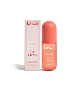 Rounded coral-colored bottle and soft pink box of Kitsch Tart Cherry scent Hair Perfume with white and red lettering respectively