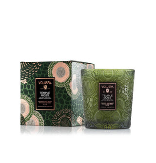 Embossed green glass Temple Moss Voluspa candle vessel next to its matching green and gold floral-patterned gift box