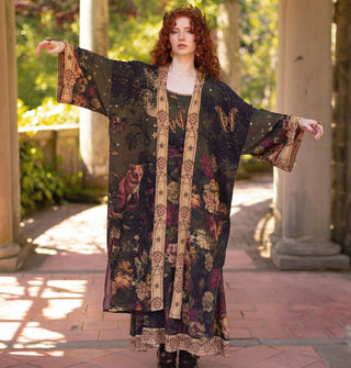 Model with arm outstretched wears a long, kimono-style robe featuring florals, butterflies, and a fox with contrasting print borders