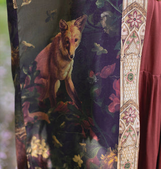 Detail of a fox among flowers on a garment with contrasting stained glass-style printed border