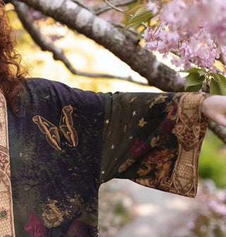 Model's outstretched arm reveals the design details of a kimono-style robe with butterfly, florals, and stars throughout, complemented by a printed cuff