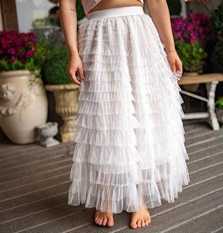 Model wears an ankle-length white tiered tulle skirt with elastic waistband