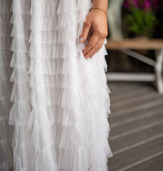 Model wears an ankle-length white tiered tulle skirt with elastic waistband