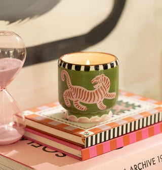 Lit tiger jar candle atop a stack of books next to an hourglass