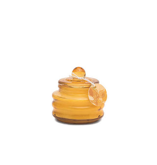 Ribbed gold glass candle jar with round tag hanging from its knobbed lid