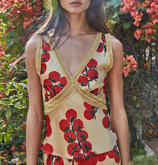 Model wears a cream-colored camisole top with deep V-neck, lace details, and print of red tomatoes on the vine