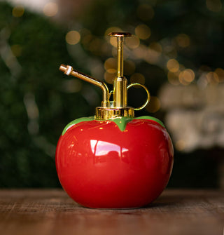 Plant mister with gold top hardware and a a ceramic base designed to resemble a red tomato with green leaves