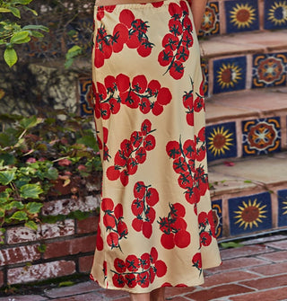 Model wears a tan satin midi-length skirt featuring a print of red tomatoes on the vine against a Tuscan-style backdrop