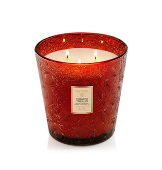 Lit Tomato Trellis Voluspa candle with three wicks in a red embossed glass vessel