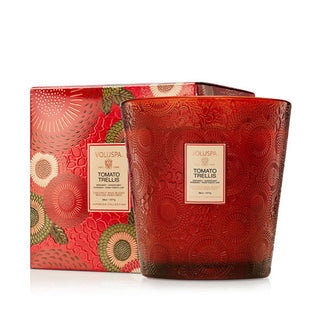 Tomato Trellis Voluspa candle in red embossed glass vessel alongside its matching gift box with red, green, and gold floral patterning