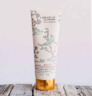 White bottle of Library of Flowers True Vanilla Shower Gel with bronze-colored cap features illustration of blue birds in flight and perched on branches