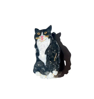 Hair clip designed to resemble a black and white tuxedo cat with gold and pink facial details