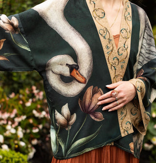 Model wears a cropped robe printed with large swan and flower design complemented by a printed border and sleeve cuff