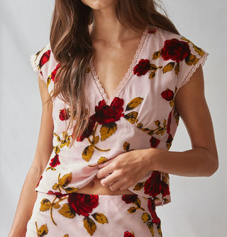 Model wears a cap-sleeved blouse with lace trim, empire waist, and bold red rose print