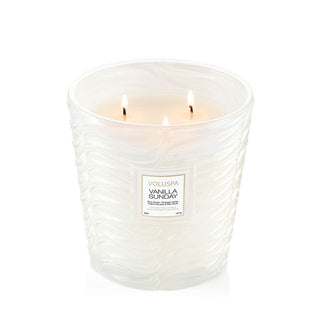 Lit three-wick Vanilla Sunday Voluspa candle in a frosted white embossed glass vessel