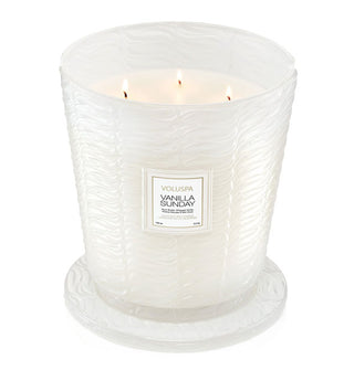 Lit multi-wick Vanilla Sunday Voluspa candle in frosted white embossed glass vessel with matching lid underneath serving as a coaster