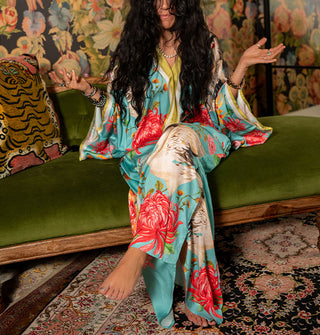Seated model wears a long, silky blue robe with bold floral and crane print