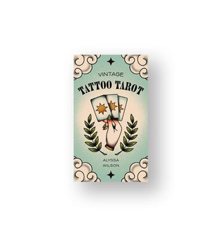 Vintage Tattoo Tarot deck box features illustration of a hand holding three cards with star symbols on them flanked by fern leaves and, at the outermost corners, white clouds