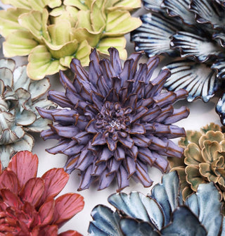 Purple ceramic chrysanthemum flower wall art sculpture surrounded by other styles and colors