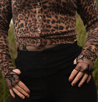 Model wears a leopard print button-down cardigan layered with a sheer black floral lace long-sleeved top with thumbholes